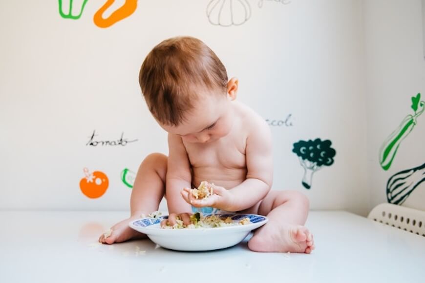 baby eating on his own while being seated